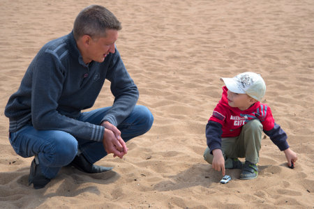 SAINT PETERSBURG, RUSSIA - JUNE 21, 2015: Father and young son playing cars in the sandのeditorial素材
