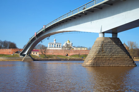 Pedestrian bridge over the Volkhov river against the background of the Kremlin of Veliky Novgorod Sunny April day. Russiaのeditorial素材