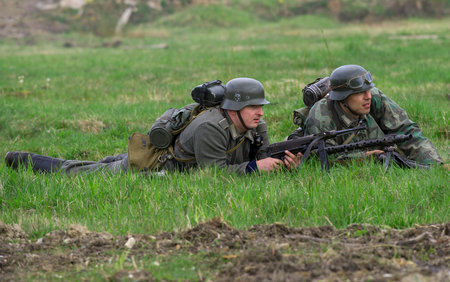 SAINT PETERSBURG, RUSSIA - MAY 05, 2015: German infantryman and machine gunner lay down in the grass. Reconstruction of the episode of the great Patriotic warのeditorial素材