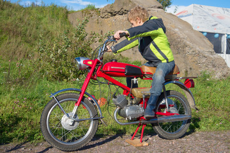 KRONSTADT, RUSSIA - SEPTEMBER 04, 2016: The teenager sits on the old Ñoviet moped "Verkhovyna-6". Exhibition of retro transport in Kronstadtのeditorial素材
