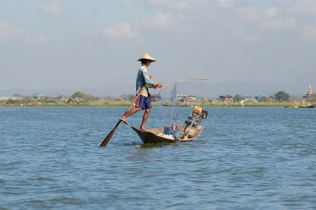 INLE LAKE, MYANMAR - DECEMBER 20, 2016: A fisherman in a boat unravels the fishing networkのeditorial素材
