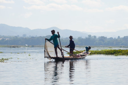 INLE LAKE, MYANMAR - DECEMBER 26, 2016: Two Burmese fisherman in traditional wooden boat. Inle Lake, Myanmarのeditorial素材