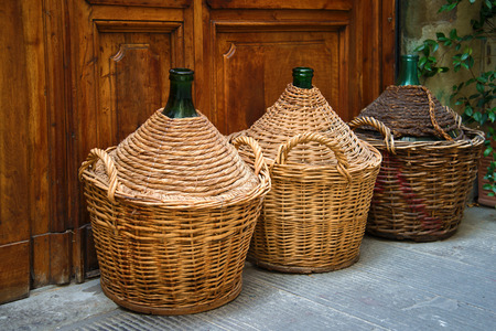 Three braided wine bottles near the wooden door close-up. Italyの写真素材