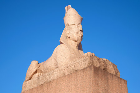 Ancient Egyptian Sphinx with University embankment close-up against a blue sky. Saint-Petersburg,...