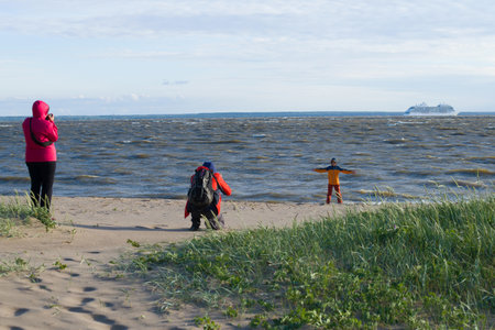 SAINT-PETERSBURG, RUSSIA - JUNE 20, 2018: A family is photographed on the shore of the Finnish bay on a windy summer day. Kronstadtのeditorial素材