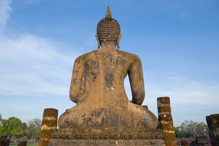 View from the back of ancient sculpture of a sitting Buddha against  blue sky. Sukhothai, Thailandのeditorial素材