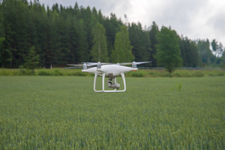 Quadrocopter flies over a green field on a cloudy summer day