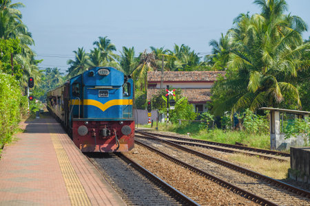 HIKKADUWA, SRI LANKA - FEBRUARY 21, 2020: A passenger train arrives on the railway station on a sunny afternoon.のeditorial素材