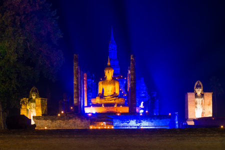 Sculpture of Buddha in blue night illumination on the ancient ruins of the Buddhist temple of Wat Mahathat. Historical Park of Sukhothai city, Thailandの写真素材