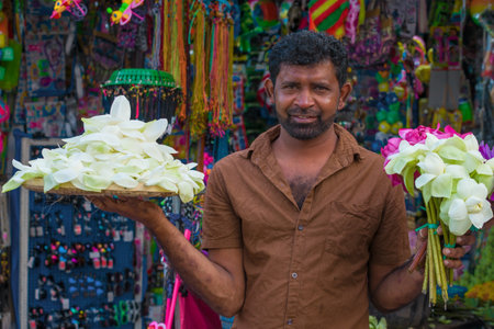 ANURADHAPURA, SRI LANKA - FEBRUARY 04, 2020: Street vendor offers flowers for religious offering to Buddhaのeditorial素材
