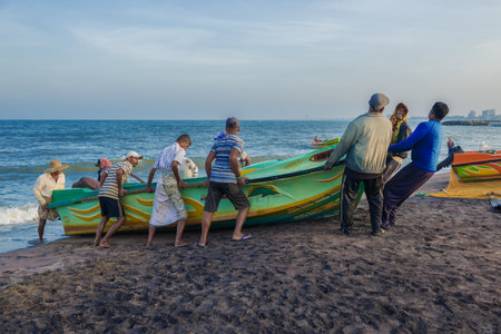 NEGOMBO, SRI LANKA - FEBRUARY 03, 2020: Fishermen pull the boat to the sandy shore of the ocean after fishingのeditorial素材