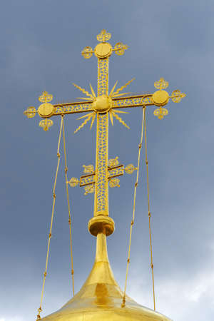 A cross on the dome of Trinity Cathedral against a cloud sky. Holy Trinity St. Sergius Lavra,...