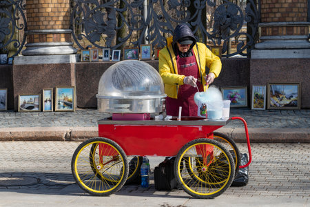 SAINT PETERSBURG, RUSSIA - APRIL 03, 2022: A street vendor prepares a portion of cotton candy on a sunny April dayのeditorial素材