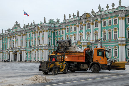 SAINT PETERSBURG, RUSSIA - DECEMBER 20, 2022: A forklift loads the removed snow into a truck at the Winter Palace on a cloudy December day. palace squareのeditorial素材