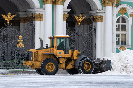 SAINT PETERSBURG, RUSSIA - MARCH 06, 2023: Volvo L60F heavy loader shovels snow at the entrance to...