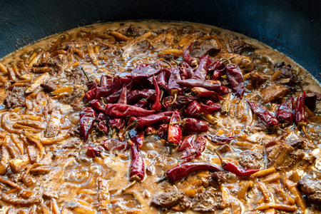 Hot red pepper pods in boiled meat with vegetables. One of the stages of cooking Uzbek pilaf....