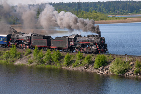 HELULYA, RUSSIA - JUNE 11, 2022: Two old soviet "L" series steam locomotives of the "L" series in motion on the KarmalanjÃ¤rvi lake dam on a sunny June day. Kareliaのeditorial素材