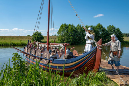 TVER REGION, RUSSIA - JULY 23, 2022: Ancient Russian boat with warriors at the pier on the Buyanka river on a sunny summer day. Historical festival "Epic Coast"のeditorial素材