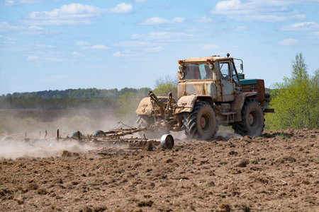 PSKOV REGION, RUSSIA - MAY 07, 2023: Old T-150K (Soviet agricultural wheeled tractor) harrows a plowed field on a sunny May dayのeditorial素材
