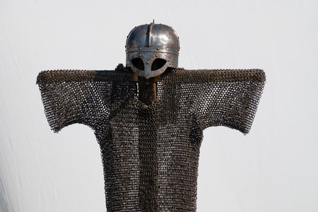 Early medieval viking helmet and chain mail on a hanger on a white background. Reconstruction of...
