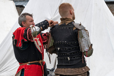 SHLISSELBURG, RUSSIA - JULY 29, 2023: Squire fixes knight's armor before battle. Historical festival...