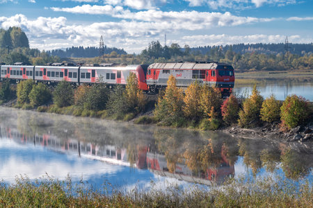 SORTAVALA, RUSSIA - OCTOBER 01, 2024: Diesel locomotive TEP70BS with electric train Lastochka on the dam of Kalmaranyarvi lake on a sunny October day. Kareliaのeditorial素材