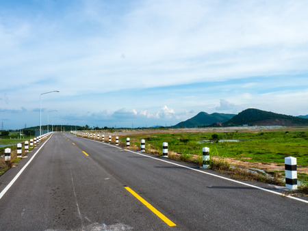 asphalt road through old dam and clouds on blue skyの写真素材
