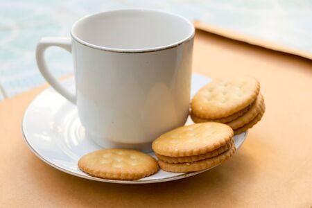 Cup of coffee and a cookie is placed on the envelopeの写真素材