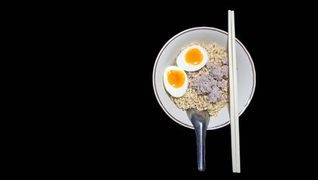 Instant noodles in bowl with boiled egg and minced pork on black backgroundの写真素材