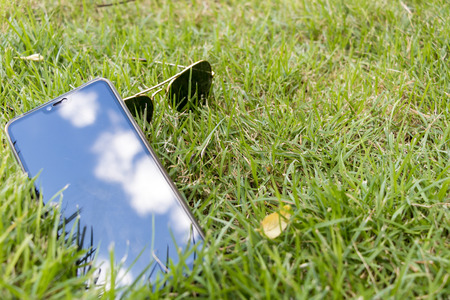 Relaxation at the eyes and brain.Glasses and phone placed on the lawnの写真素材