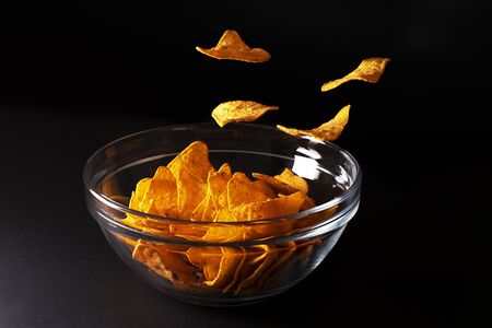 Nachos in a bowl on black backgroundの写真素材