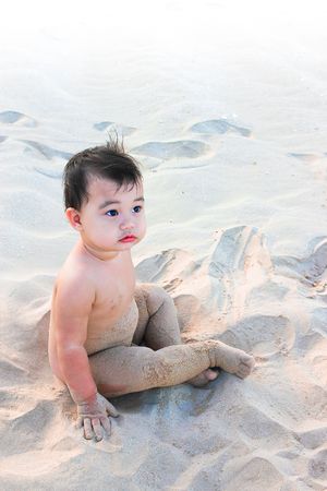 boy enjoy playing sand alone on beachの写真素材