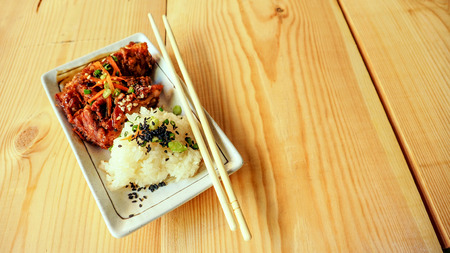 Sticky rice and fried chicken macro photo focus select at Topping has sesame, spring onions and carrot on top ceramic plate, On wood.の写真素材