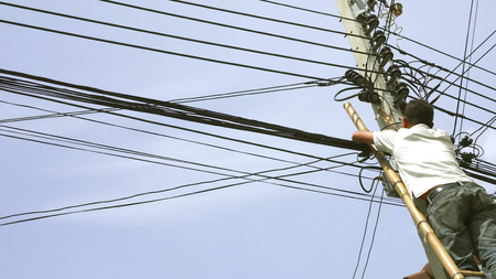 Asian Electronics technician he working to install internet fiber optic and climbing by the bamboo...