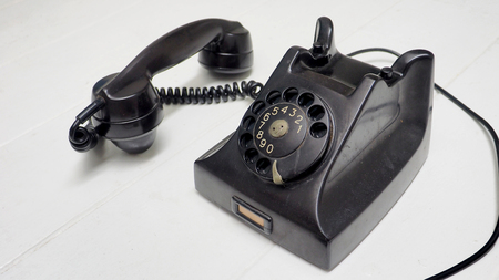 Telephone antique black color and speaker lift out to show option is button, Isolate on white wood floor has copy space.の写真素材