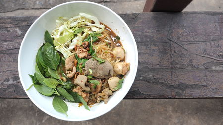 Boat noodles pork Thai food classic and popular menu and ready to eat in white bowl on vintage wood...