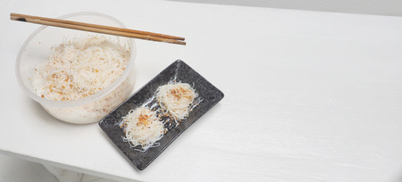 Rice noodles steamed mix oil from garlic chicken fried with seasoning and saseme ripe, In Japanese ceramic black plate isolate on white wood, Photo soft tone color for background and has copy space.の写真素材