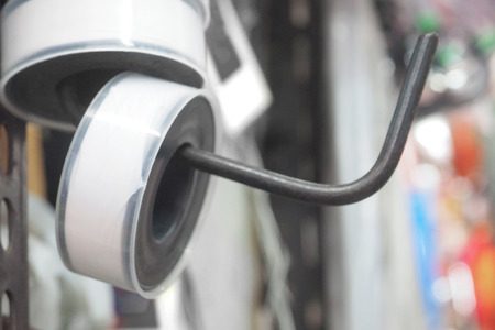 Pipe thread tape hanging on hook for sale in Thailand hardware shop, Macro photo focus select at object blur background, has copy space.の写真素材