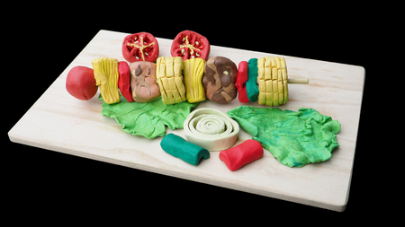 Mold clay create art of food is BBQ grill raw material has tomato, corn, lettuce, onion, serve on wooden board has clipping path.の写真素材