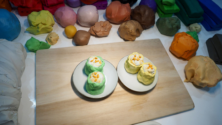 Mold clay food is Steamed Dumpling, dim sum shrimp 2 yellow and green create art of sculpture activity, on wooden board, Macro photo focus select at object background are blur of clays many color.の写真素材