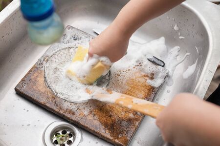 two hands washing colander and wooden chopping board in the metal sinkの写真素材