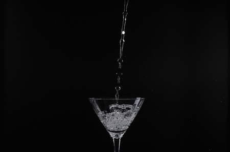 pouring water into glass with black backgroundの写真素材