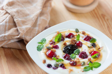 Yogurt with berries and mint on wood table.の写真素材