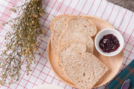 Sliced hole wheat bread in wood dish on table.