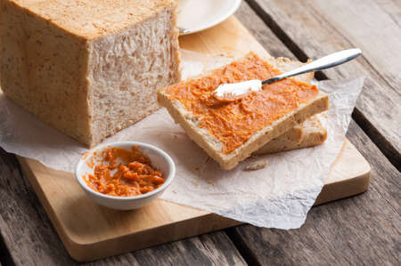 Sliced whole wheat bread in wood board with Thai tea cream on table.の写真素材