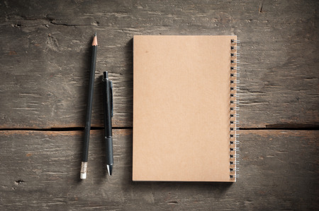 Small notepad with pen and pencil on rustic wood background with low key scene.の写真素材