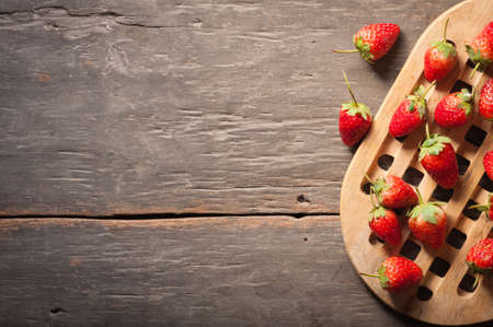 Strawberries on wood background in vintage style with low key scene.の写真素材