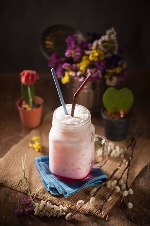 Fresh milk with red syrup on wood table in cafe with low key sceneの写真素材