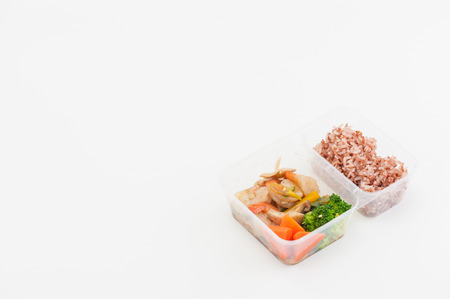 Thai style spicy stir fried shrimps cooked by clean food concept with brown rice and vegetables in lunch box on white tableの写真素材