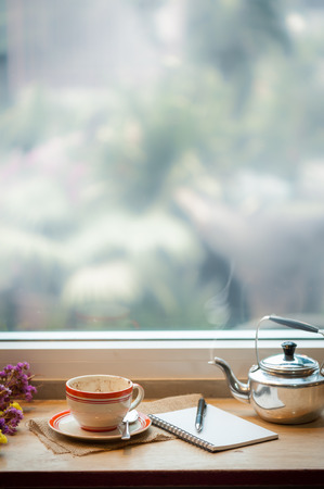 Coffee cup and opened notebook on wood bar at coffee shop in morning time of winter seasonの写真素材